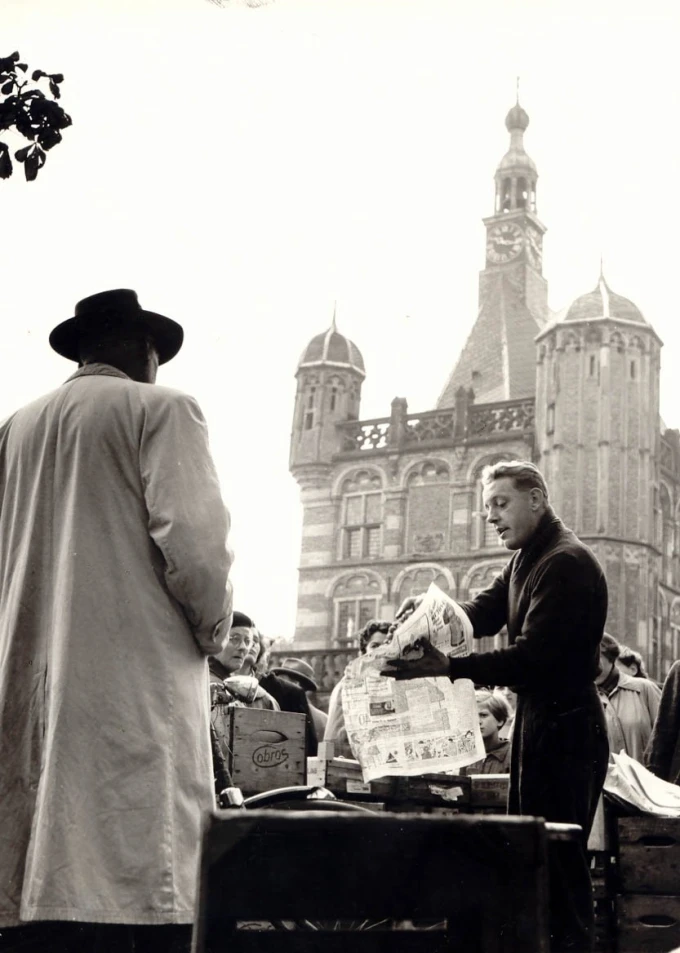 Zwart wit/sepia foto van mensen voor de kerk in Deventer, man staat met krant.